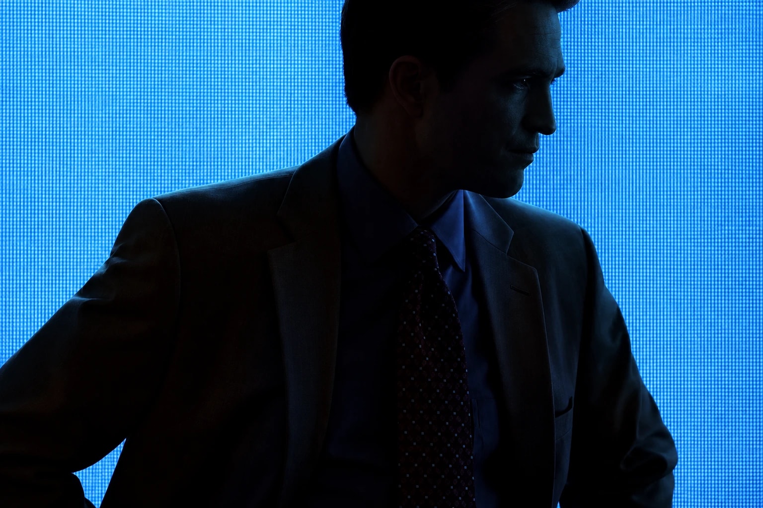 Still from Primetime: a man in a suit and tie, silhouetted against a glowing blue screen